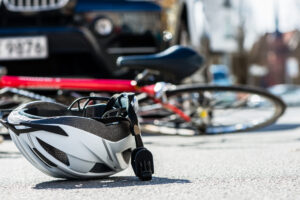 Columbia Bicycle Accident Lawyer with a fallen bike under a car and helmet